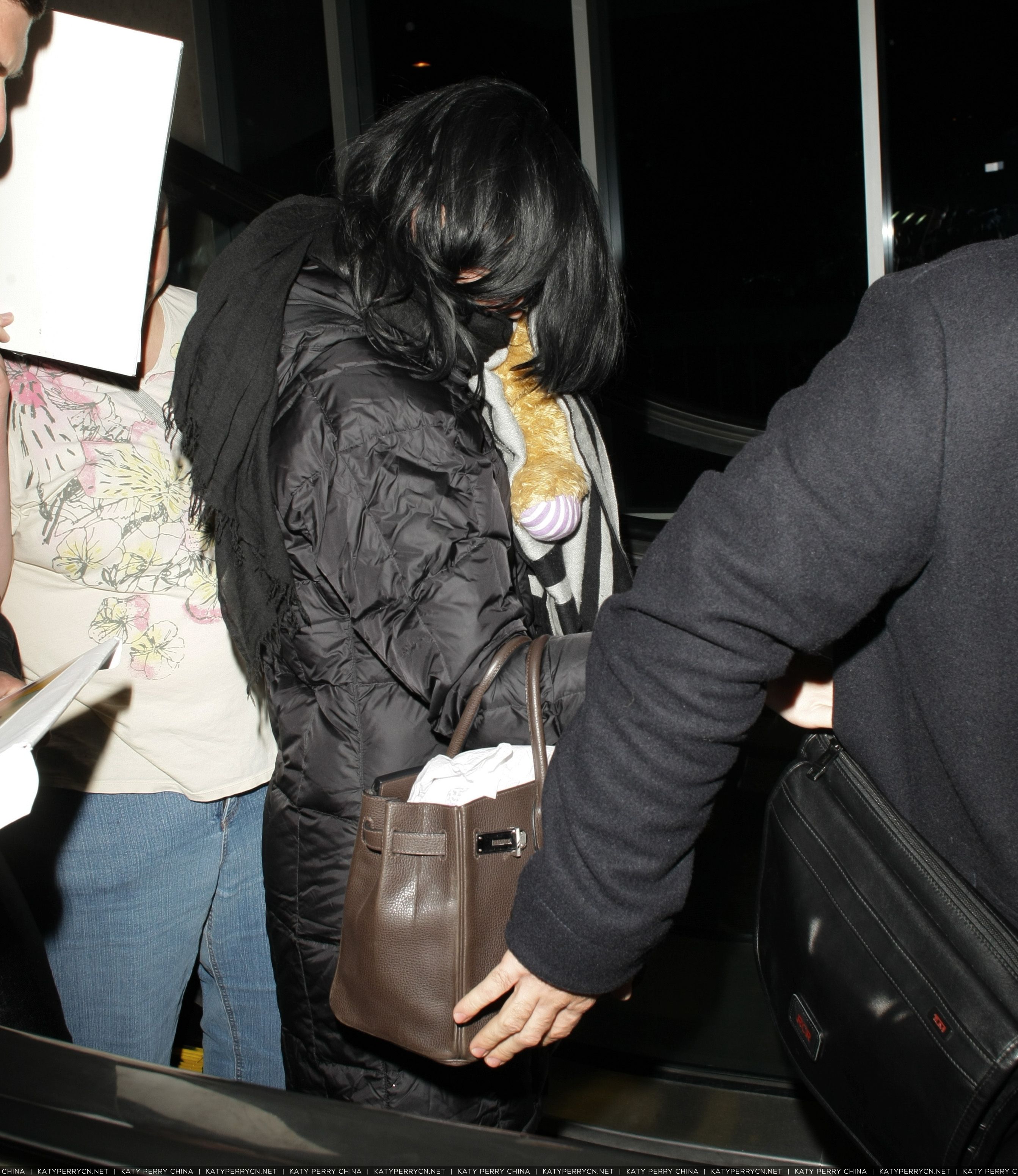 Katy Perry抵达洛杉矶国际机场后躲在毯子下和护送人员身后